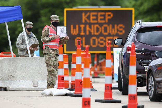 National Guard member holds up a sign at a coronavirus testing site 