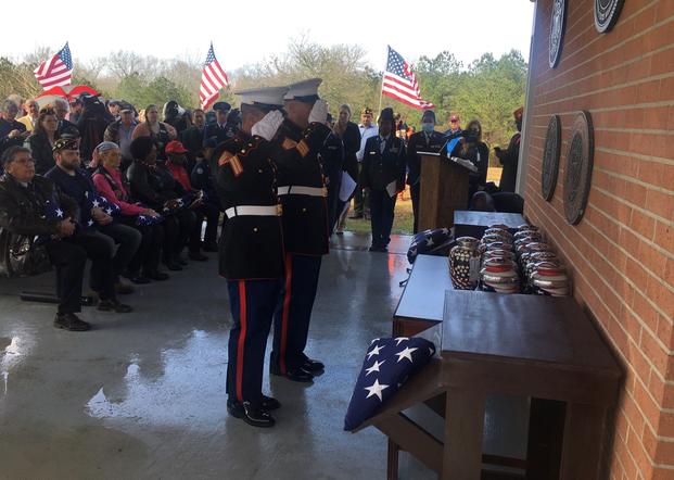 Marine honor guard members salute urns containing the ashes of veterans awaiting entombment.