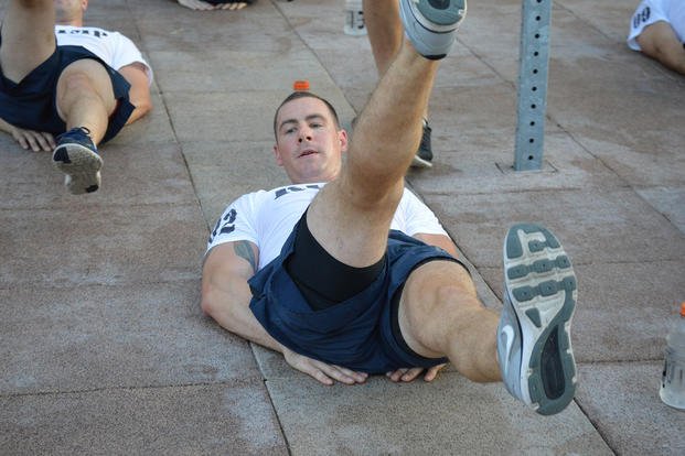 A Navy sailor completes flutter kicks during morning physical fitness training.