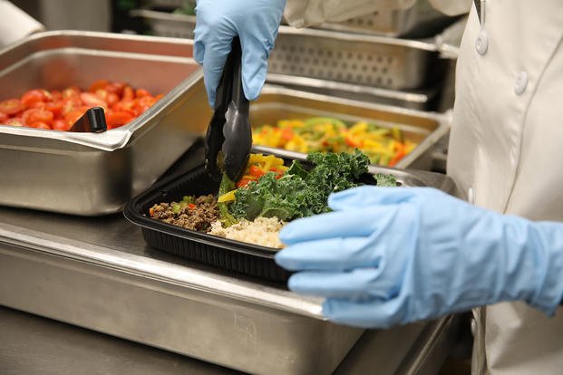 A culinary specialist adds the final touch to a Meal Prep to-go meal.