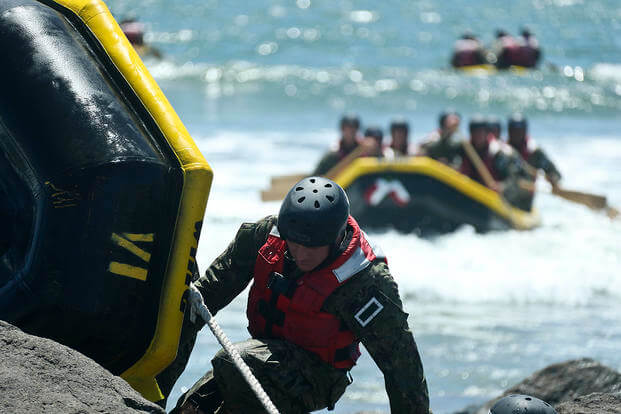 SEAL candidates participate in a rock portage evolution during Basic Underwater Demolition/SEAL (BUD/S) training.
