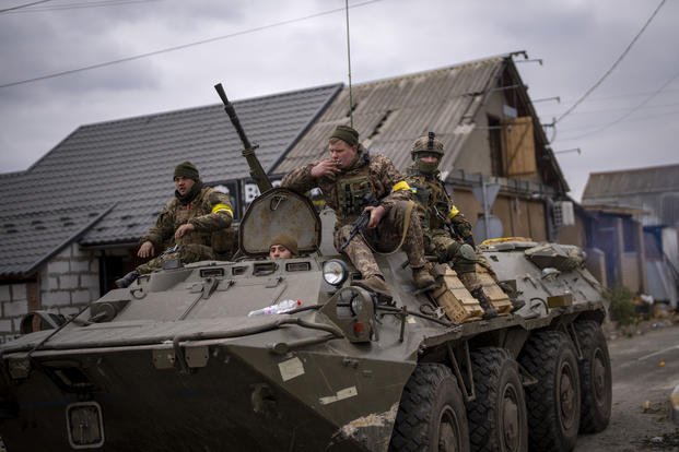Ukrainian soldiers drive on an armored vehicle in the outskirts of Kyiv.