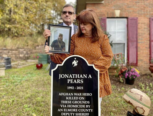 Andy and Mary Pears stand with a photo of their son by the memorial to him