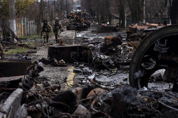 Soldiers walk amid destroyed Russian tanks in Bucha, on the outskirts of Kyiv, Ukraine.