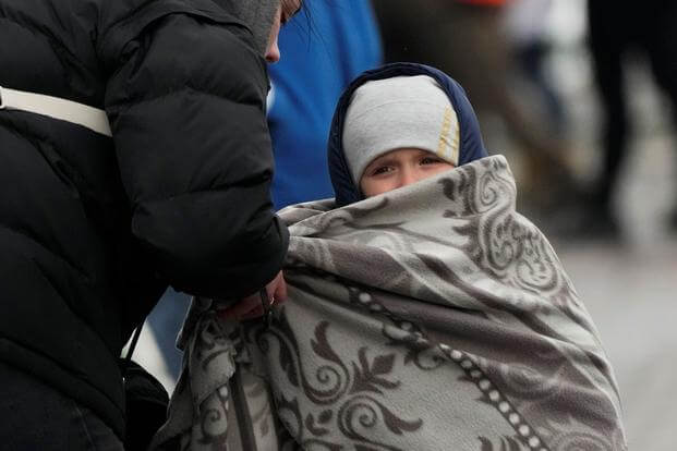 A woman covers her son with a blanket at the border crossing in Poland.