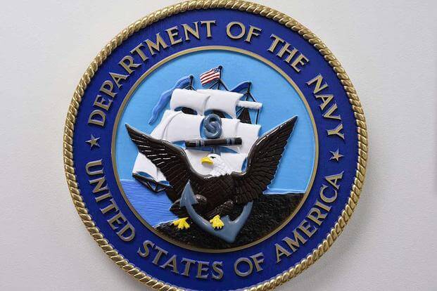 United States Department of the Navy emblem hanging on a wall.