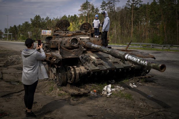 kids on top of a destroyed Russian tank, on the outskirts of Kyiv, Ukraine
