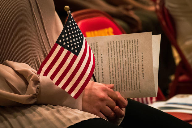 A U.S. Status of Forces Agreement personnel holds the U.S. flag during a naturalization ceremony hosted at the Camp Foster Community Center on Camp Foster, Okinawa, Japan, Feb. 18, 2022.