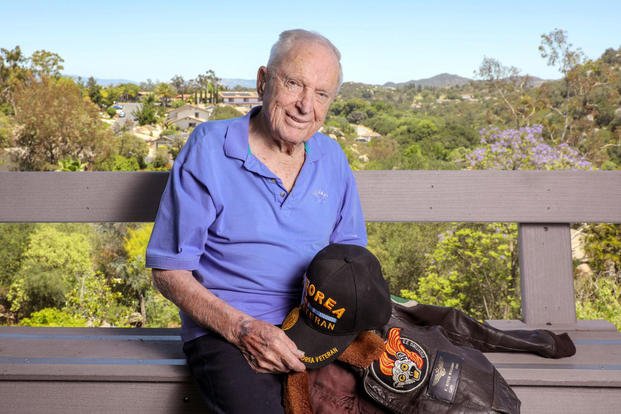 Veteran Royce Williams, 97, holds one of his many caps and his flight jacket.