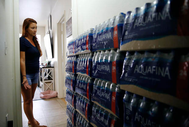 A woman looks at a wall of bottled water. 