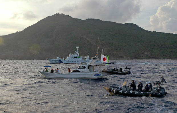 Japanese Coast Guard vessels and boats sail alongside a Japanese activists' fishing boat