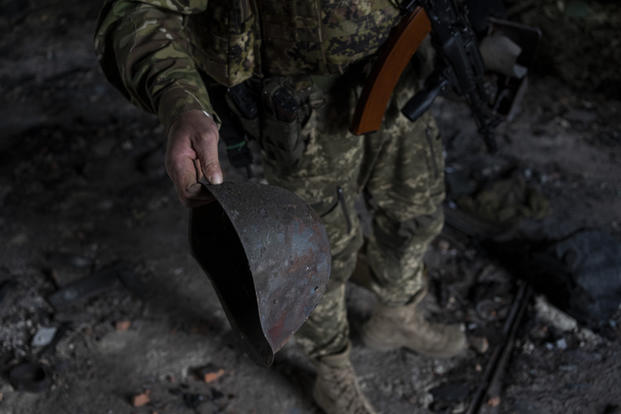 A Ukrainian serviceman holds the helmet used by Russian troops.