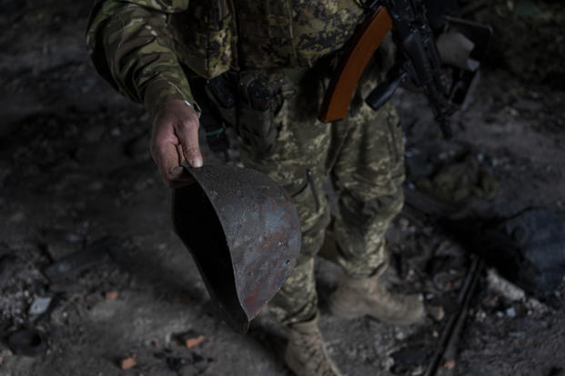 A Ukrainian serviceman holds the helmet used by Russian troops inside a school damaged during a battle between Russian and Ukrainian forces in the village of Vilkhivka, on the outskirts of Kharkiv, in eastern Ukraine, May 20, 2022. (AP Photo/Bernat Armangue) A Ukrainian serviceman holds the helmet used by Russian troops.