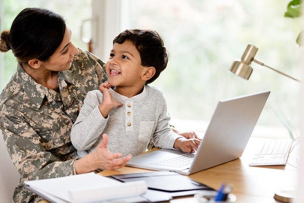 Military mother with child on lap and laptop on desk
