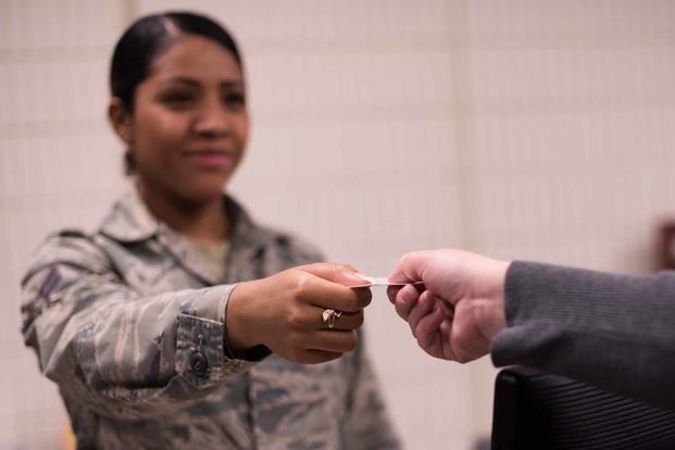 Airman hands a military dependent a new identification card.