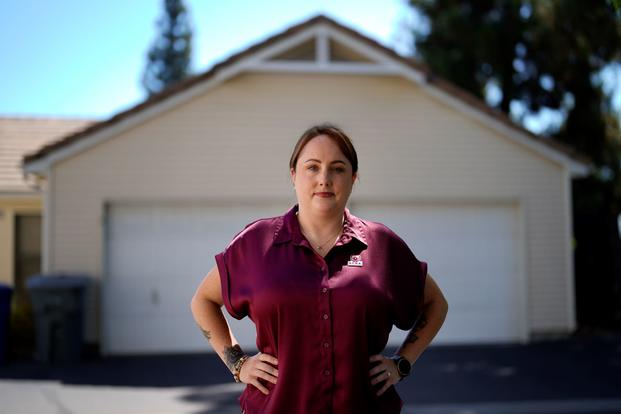 Kate Needham, who co-founded Armed Forces Housing Advocates, stands in front of a house.