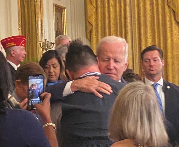 President Joe Biden consoles Sri Benson, husband of Katie Benson, an Army veteran who died July 9, 2022, of mesothelioma, linked to her service in Kuwait. 