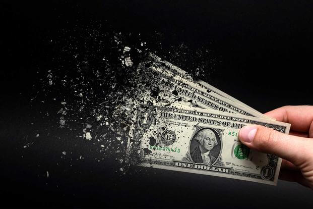 Dollar bill disintegrating to represent loss of value due to inflation 