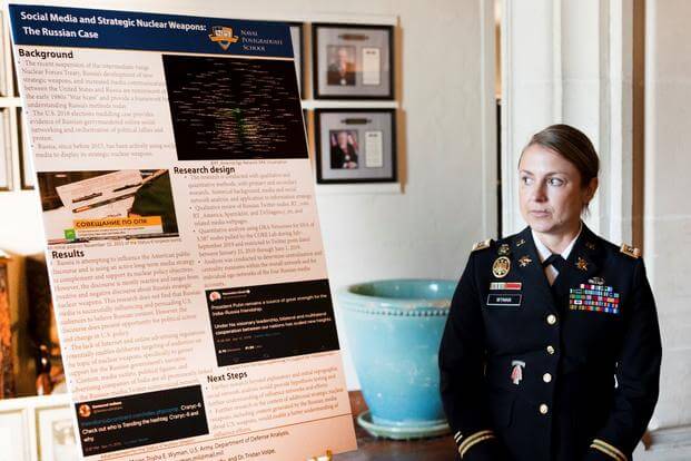 An Army officer stands next to a poster at the Naval Postgraduate School in Monterey, California.