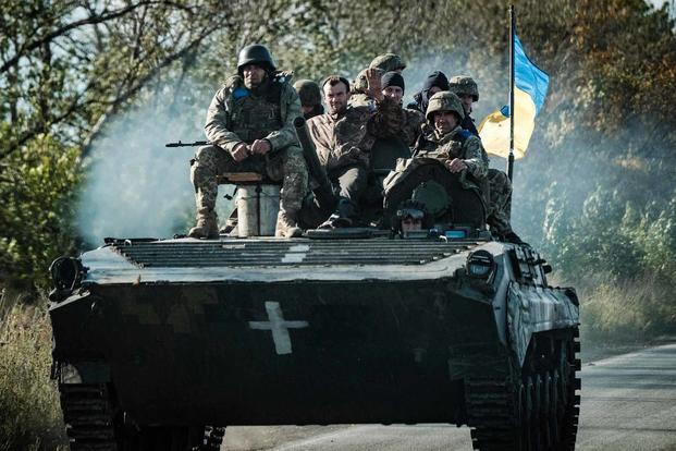 Ukrainian soldiers ride on an armored vehicle in Novostepanivka.