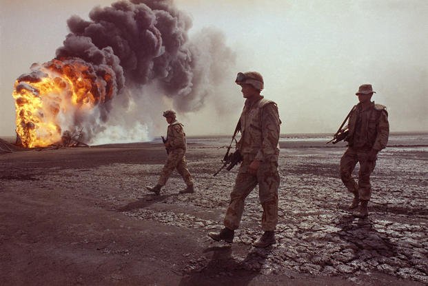 Marines walk across a flaming desert plain in Kuwait in 1991.