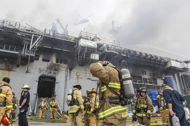 Sailors and federal firefighters respond to a fire on board the amphibious assault ship USS Bonhomme Richard (LHD 6) at Naval Base San Diego.