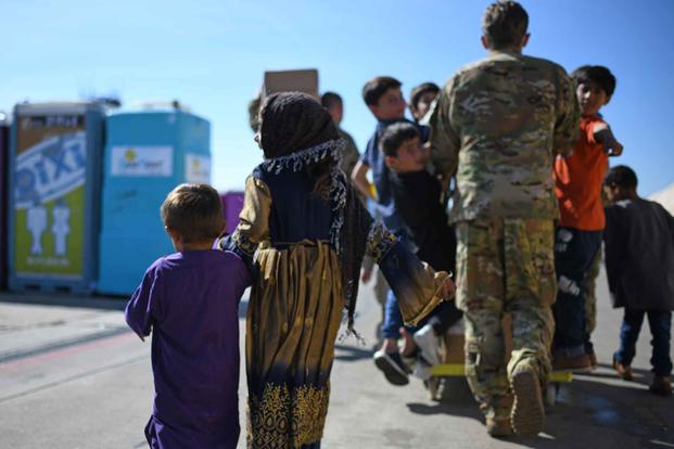 Afghan sister and brother walk hand in hand during evacuation.