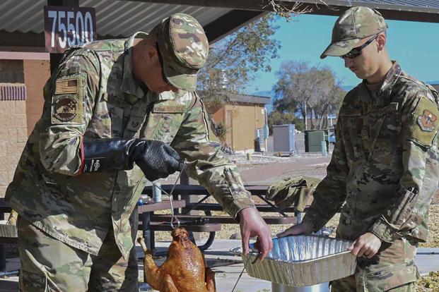Airmen prepare a turkey for a Thanksgiving meal.