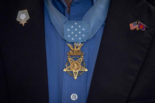 A Medal of Honor hangs on recipients chest.