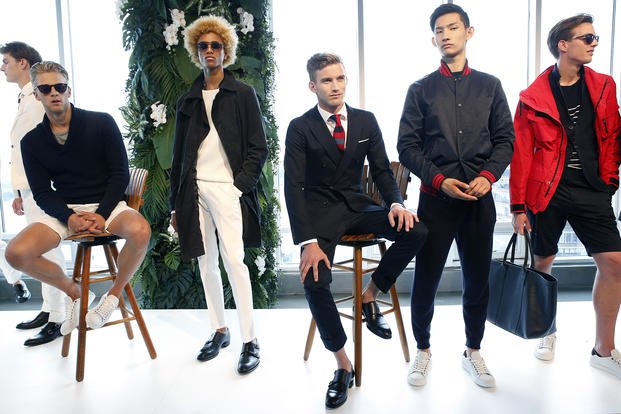 Models wearing a combination of casual and business attire pose during Men's Fashion Week in New York.