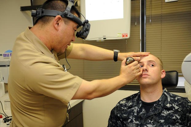 The chairman of optometry performs a binocular indirect ophthalmoscopy examination during a routine eye exam on Petty Officer 3rd Class Andrew Harris at Naval Medical Center San Diego.