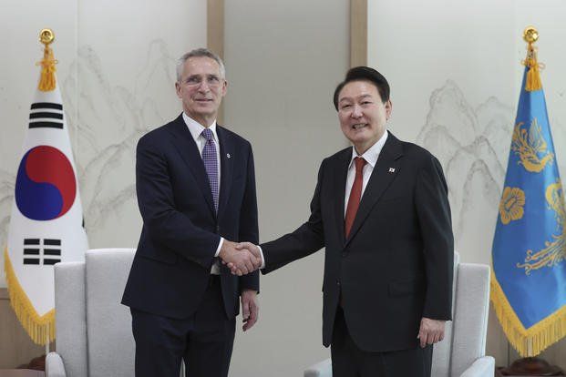 South Korean President Yoon Suk Yeol, right, shakes hands with NATO Secretary-General Jens Stoltenberg