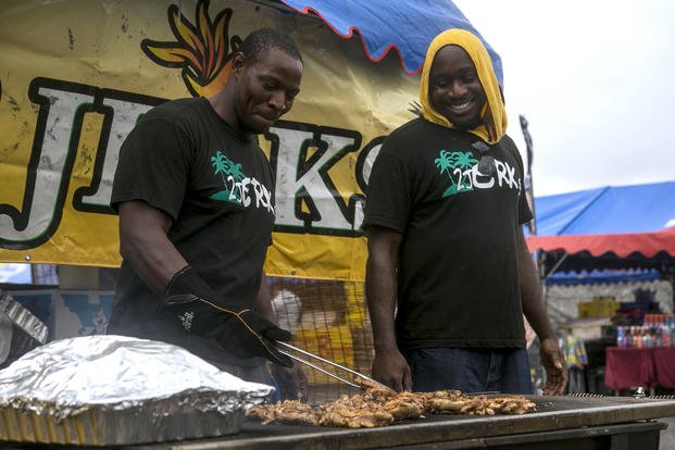 Retired Staff Sgt. Fredrick I. Simpson, left, and Jamie Gibson grill outside of their 2 Jerks tent at the Camp Foster Festival in Okinawa, Japan.