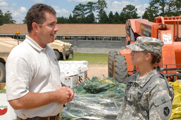 Iowa Congressman Bruce Braley speaks to 2nd Lt. Elisabeth Bloomfield, a soldier with Bravo Co. 334 Brigade Support Battalion, Iowa National Guard, in front of the corn and watermelons donated to the Guardsmen training at Camp Shelby Joint Forces Training Center, Mississippi.