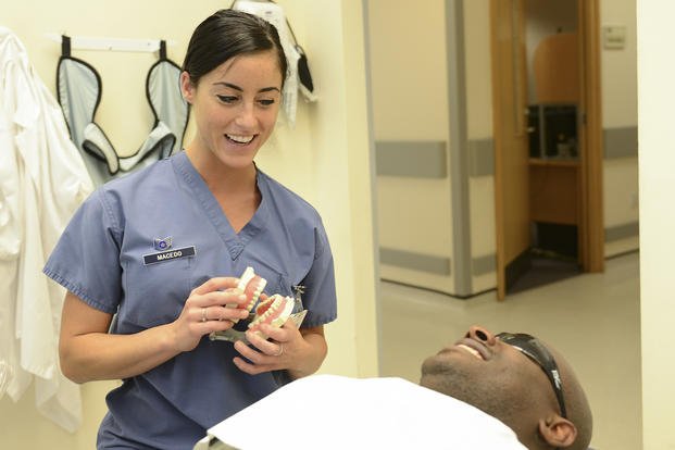 A dental hygienist briefs a patient on a dental cleaning procedure.