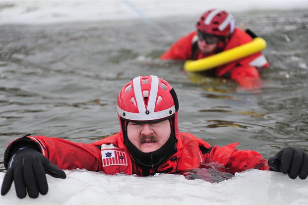 Coast Guard Chief Petty Officer Jason Betzing waits for a fellow Coast Guardsman to rescue him from a hole in the ice-covered Saginaw Bay in Lake Huron during ice rescue training.
