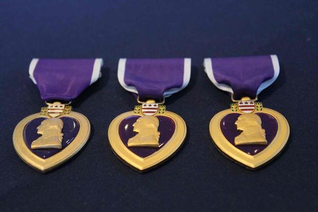 Three Purple Heart Medals displayed in a box.