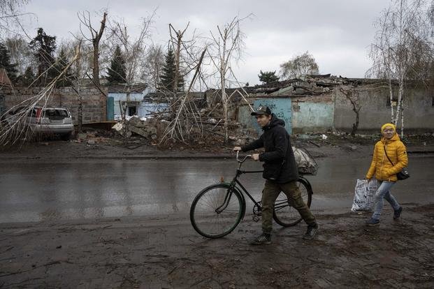 Locals walk past a house which was destroyed by Russian attack in Ukraine.