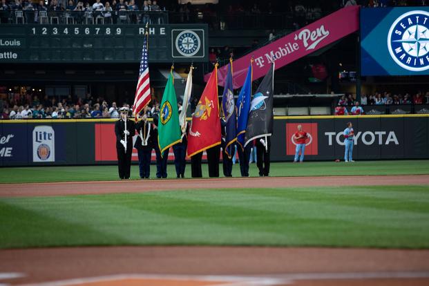 A military color guard stands on the field at a baseball game