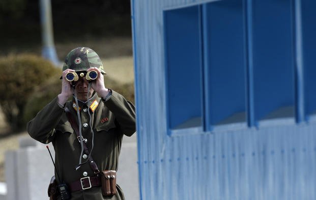 North Korean soldier looks through a pair of binoculars at Panmunjom