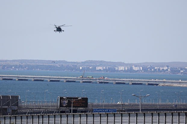 A Russian military helicopter flies over damaged parts of Crimean Bridge 