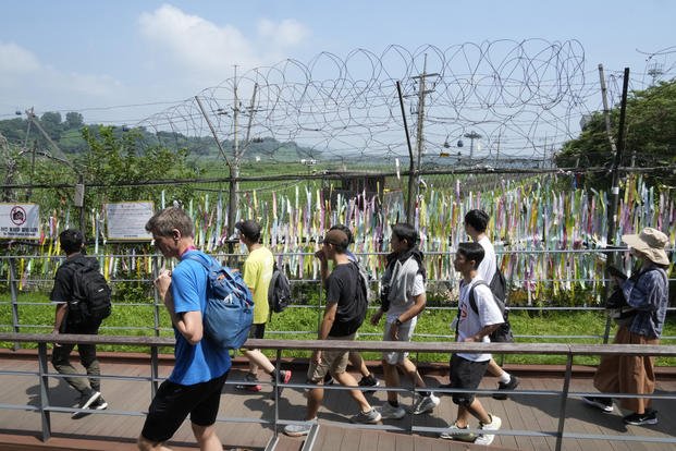 Visitors pass by a wire fence decorated with ribbons written with messages wishing for the reunification of the two Koreas at the Imjingak Pavilion