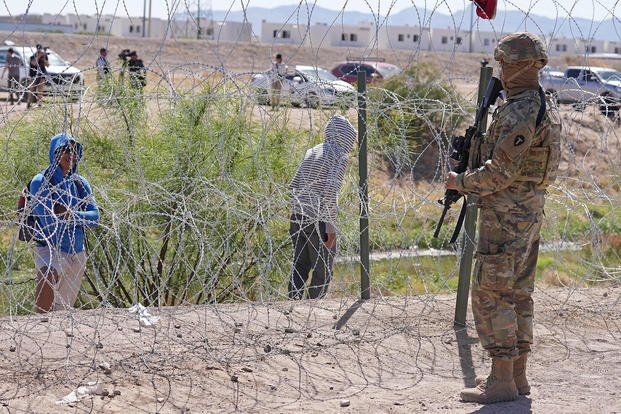 People look across the border from Mexico at the Texas Army National Guard soldiers with Gov. Greg Abbott’s self-styled Texas Tactical Border Force during Operation Lone Star Task Force West, May 11, 2023, near El Paso, Texas.