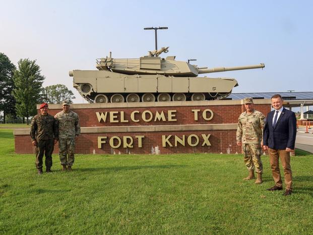 From Left: Polish Land Forces Maj. Gen. Adam Joks, V Corps Deputy Commanding General of Interoperability, U.S. Army Command Sgt. Maj. Raymond S. Harris, V Corps command sergeant major, U.S. Army Lt. Gen. John S. Kolasheski, U.S. Army V Corps commanding general, and Polish Minister of National Defense Mariusz Błaszczak pose for a photo near Fort Knox's welcome sign, Fort Knox, Kentucky, July 17, 2023.