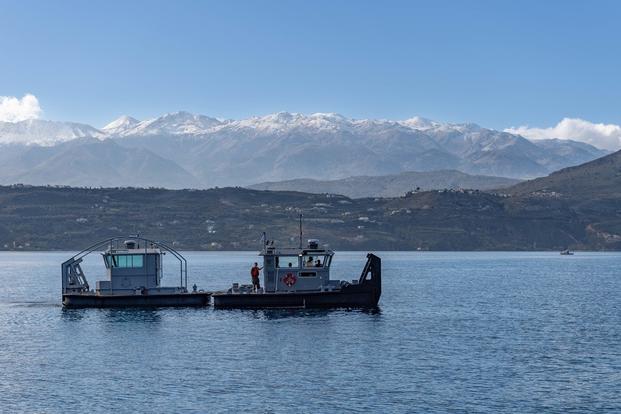 Sailors assigned the Naval Support Activity (NSA) Souda Bay’s Port Operations Team use a new 30-foot Modutech barrier boat to tow an old barrier boat to the pier for disposition near the NATO Marathi Pier Complex in Souda Bay, Crete, Greece. 