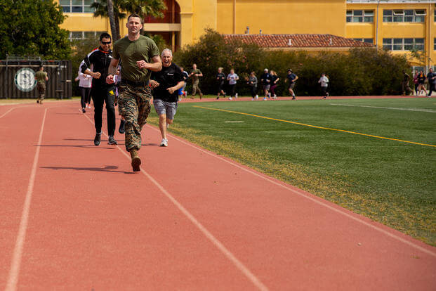 Attendees of Marine Corps Recruit Depot (MCRD) San Diego's Educators Workshop run on a track during a mock combat fitness test.