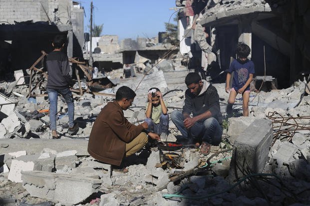 Palestinians cook bread by their destroyed homes in Kuza' a Gaza Strip during the temporary ceasefir