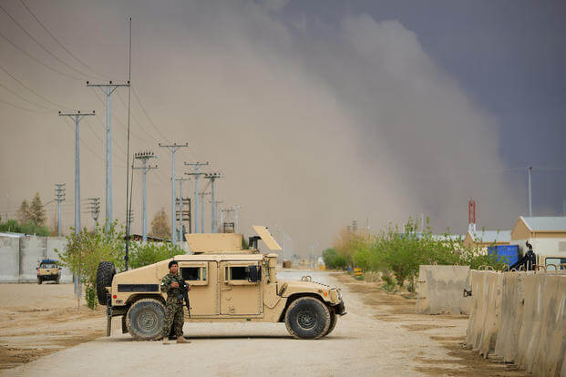 An Afghan National Army (ANA) soldier, assigned to the 215th Corps, stands next to an ANA Humvee while guarding the Operational Coordination Center-Regional (OCC-R) during the Afghan presidential elections as a sandstorm approaches aboard Camp Shorabak, Helmand province, Afghanistan, April 5, 2014. (Lance Cpl. Darien J. Bjorndal/U.S. Marine Corps photo)