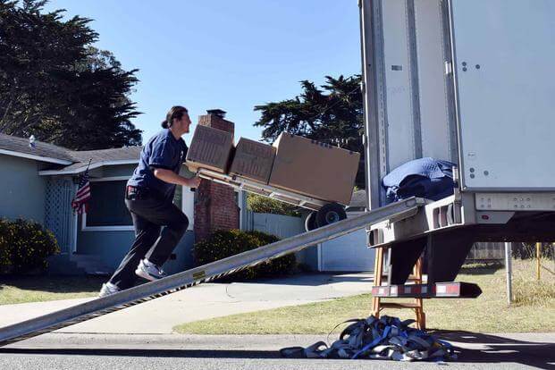 Movers load a service member’s household goods into a moving truck