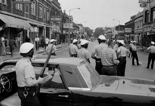 Police blockade a street on Detroit's Near West Side, about three miles from the downtown area, throwing stones and bottles at store fronts